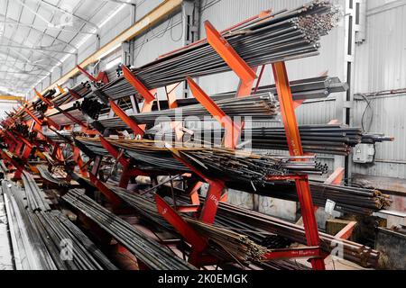 Dünne Metallstäbe stapeln sich auf einem großen Regal im Kühllager Stockfoto