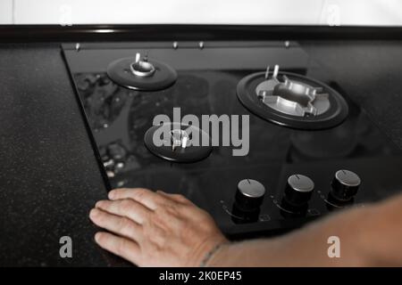 Installation eines eingebauten Gasherd mit drei Brennern in einer schwarzen Arbeitsplatte. Küchenausstattung. Stockfoto