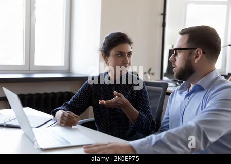 Zwei seriöse, vielfältige Mitarbeiter diskutieren über die Aufgaben von Geschäftungsprojekten Stockfoto