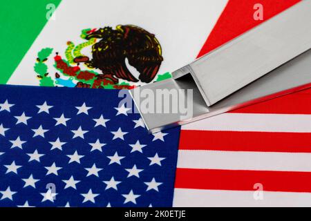 Aluminium-Metalllager auf Flaggen von Mexiko und den Vereinigten Staaten von Amerika. Konzept von Handelskrieg, Zöllen, fairem Handel und Stahlindustrie. Stockfoto