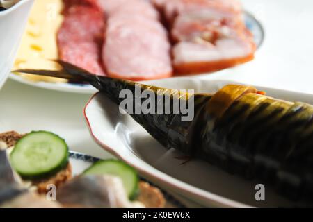 Unschärfe-Effekt bei geräucherter Makrele. Geräucherter Fisch mit Gewürzen auf dunklem Hintergrund auf dem Festtagstisch. Nahaufnahme. Fisch-Bonito. Nicht fokussiert. Stockfoto