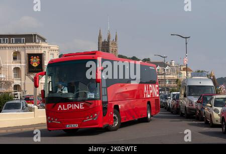 Teignmouth, Devon, England, Großbritannien. 2022. Roter Reisebus fährt durch die Küstenstadt Teignmouth im Süden von Devon, England, Großbritannien. Stockfoto
