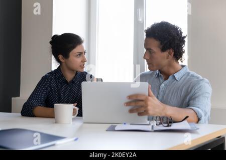 Zwei unterschiedliche Team-Kollegen teilen sich am Arbeitsplatz einen Computer Stockfoto