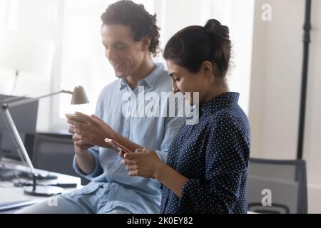 Zwei glückliche Geschäftskollegen, die Online-Apps auf Mobiltelefonen nutzen Stockfoto