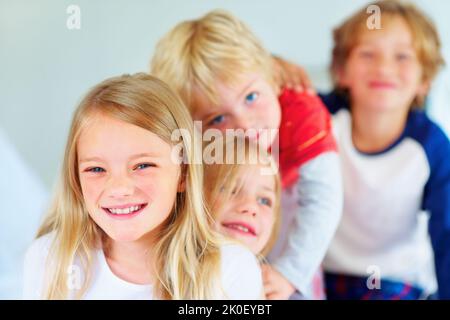 Lächelndes junges Mädchen mit ihrem Bruder und ihrer Schwester, die Schlange stehen. Porträt eines lächelnden jungen Mädchens mit ihrem Bruder und ihrer Schwester, die Schlange stehen. Stockfoto