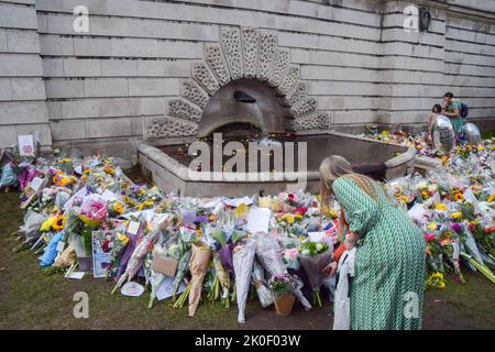 London, Großbritannien. 11. September 2022. Eine Frau hinterlässt Blumen neben einem Brunnen im St James's Park vor dem Buckingham Palace, während Tausende von Menschen weiterhin ankommen, um Königin Elizabeth II. Ihren Respekt zu erweisen Die Königin starb am 8.. September im Alter von 96 Jahren. Kredit: Vuk Valcic/Alamy Live Nachrichten Stockfoto