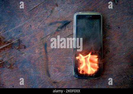 Verbranntes Mobiltelefon liegt auf dem Tisch Stockfoto