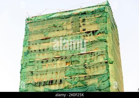 Hohes Gebäude mit Bambusgerüsten und bedeckt mit zerrissenen Gerüstnetzen, Phnom Penh City, Kambodscha Stockfoto