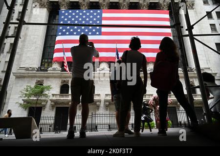 Am 11. September 2022 in New York laufen die Menschen an der amerikanischen Flagge vorbei, die vor der New Yorker Börse (NYSE) zu sehen ist. Stockfoto