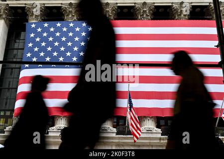 Am 11. September 2022 in New York laufen die Menschen an der amerikanischen Flagge vorbei, die vor der New Yorker Börse (NYSE) zu sehen ist. Stockfoto