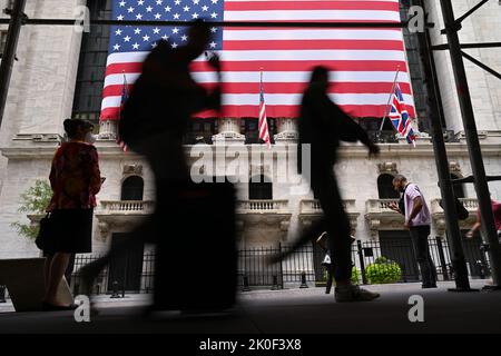 Am 11. September 2022 in New York laufen die Menschen an der amerikanischen Flagge vorbei, die vor der New Yorker Börse (NYSE) zu sehen ist. Stockfoto
