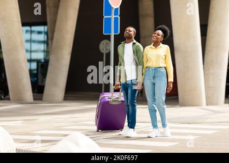 Black Millennial Ehepartner Reisen Mit Koffer In Der Nähe Des Flughafens Im Freien Stockfoto