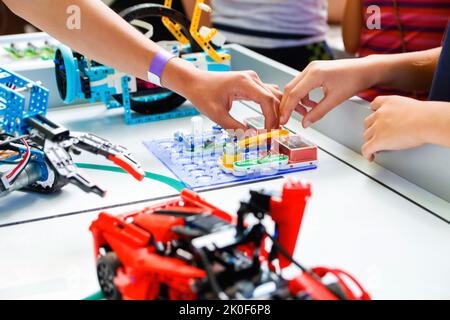 Defokussieren Kinder Hände halten bereit gemacht Roboter auf dem Tisch fröhlich smart whizzkid experimentieren mit humanoider Roboterhand, während seine Fähigkeiten zu entwickeln. Stockfoto