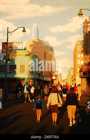 Touristen gehen zu einem realistischen, zurückblickenden Tropfen einer Hollywood-Straßenszene aus den 1930er Jahren, die auf die hohe Wand von Disneyland's California Adventure gemalt wurde Stockfoto