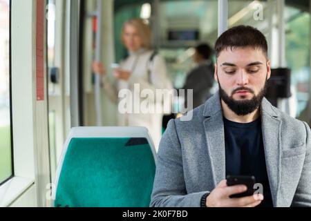 Junger Mann mit Telefon im Stadtbus Stockfoto
