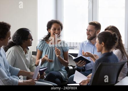 Glückliche verschiedene Süchtige sitzen auf Stühlen im Kreis, reden Stockfoto