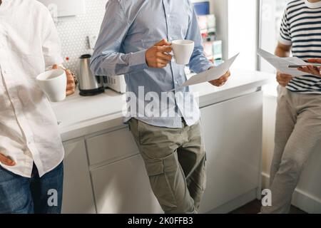 Nahaufnahme verschiedener Mitarbeiter, die in der Pause Kaffee trinken und über das Arbeitsprojekt sprechen Stockfoto