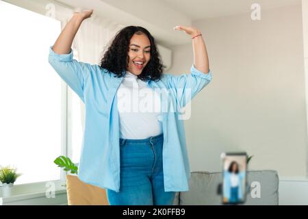 Fröhliche Schwarze Bloggerin Tanzt Beim Filmen Von Video Auf Dem Mobiltelefon Im Innen-Bereich Stockfoto