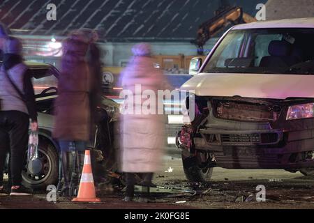 Autos stürzten bei einem Verkehrsunfall nach einer Kollision und einer Silhouette der Menschen auf der Straße der Stadt nachts stark ab. Straßenverkehrssicherheit und Versicherungskonzept Stockfoto