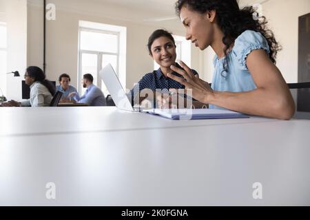 Glücklicher indischer Mentor, der Praktikant ausbilden und dabei hilft, die Arbeit zu erledigen Stockfoto