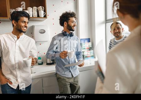 Eine Gruppe verschiedener Mitarbeiter trinkt in der Pause Kaffee und spricht über ein Arbeitsprojekt Stockfoto