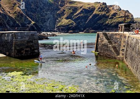 Kajakfahren im historischen Hafen von Mullion Cove in Mounts Bay Cornwall England. 13. vom August 2022. Mullion Cove oder Porth Mellin - Hafen im Westen c Stockfoto