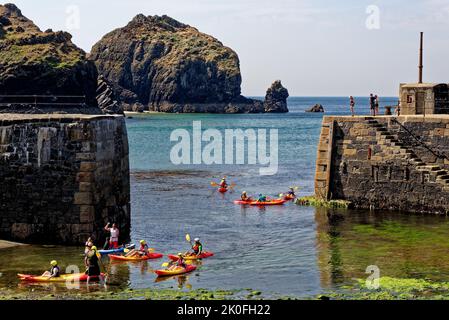 Kajakfahren im historischen Hafen von Mullion Cove in Mounts Bay Cornwall England. 13. vom August 2022. Mullion Cove oder Porth Mellin - Hafen im Westen c Stockfoto