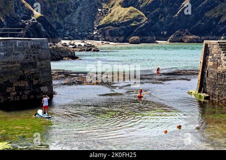 Kajakfahren im historischen Hafen von Mullion Cove in Mounts Bay Cornwall England. 13. vom August 2022. Mullion Cove oder Porth Mellin - Hafen im Westen c Stockfoto