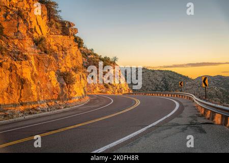 Fahren Sie eine kurvenreiche Straße entlang felsiger Klippen bei Sonnenuntergang in Mount Lemmon, Arizona. Wunderschöne Berglandschaft mit Autobahn in den Coronado National Fores Stockfoto