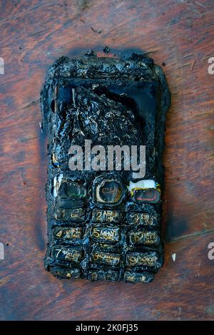 Verbranntes Mobiltelefon liegt auf dem Tisch Stockfoto