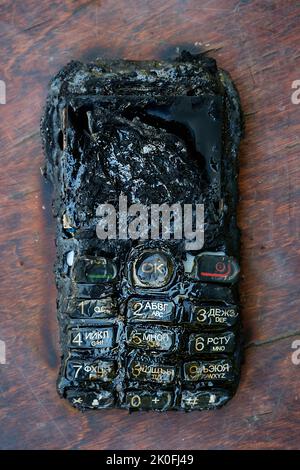 Verbranntes Mobiltelefon liegt auf dem Tisch Stockfoto