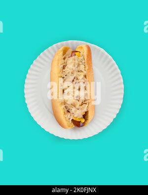 Flach Lay Hot Dog in Bun Still Life. Fankfurter in Brötchen mit Sauerkraut auf weißem Papierteller auf blauem Hintergrund mit Kopierraum. Stockfoto