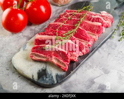 Rohe Fleischstücke auf einem Schneidebrett, reife Tomaten und Gewürze. Kochen von Gerichten aus Bio-Fleisch vom Bauernhof - Steaks, Gulasch, Suppe. Clos Stockfoto