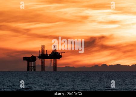 Sonnenuntergang auf der Ölplattform, Sonnenuntergang über der Lennox-Satellitenplattform in der Irischen See, Teil der Öl- und Gasbohrinseln des Douglas-Komplexes in Liverpool Bay, England, Großbritannien Stockfoto