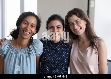 Fröhliches multiethnisches Team junger Frauen, die in Innenräumen stehen Stockfoto