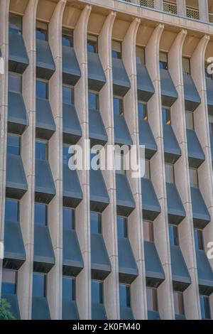 Gebäude außen mit gebogenen Wandpaneelen zwischen den Fenstern in der Innenstadt von Tucson, Arizona. Mehrstöckiges Gebäude mit beigefarbenen und schwarzen Wänden Stockfoto