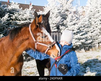 Gilr in blauer Jacke mit Fohlen auf frostiger Weide Stockfoto