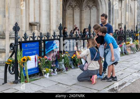 Winchester, Hampshire, Großbritannien. 11.. September 2022. Nach dem Tod von Königin Elizabeth II. Am 8.. September 2022 haben Menschen Blumen und Ehrungen zu Ehren von Königin Elizabeth II. Vor dem Eingang der Winchester Cathedral platziert. Das Land befindet sich bis zu seiner Beerdigung in einer Phase nationaler Trauer. Stockfoto