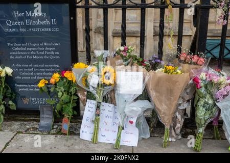 Winchester, Hampshire, Großbritannien. 11.. September 2022. Nach dem Tod von Königin Elizabeth II. Am 8.. September 2022 haben Menschen Blumen und Ehrungen zu Ehren von Königin Elizabeth II. Vor dem Eingang der Winchester Cathedral platziert. Das Land befindet sich bis zu seiner Beerdigung in einer Phase nationaler Trauer. Stockfoto