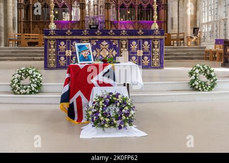 Winchester, Hampshire, Großbritannien. 11.. September 2022. Nach dem Tod von Königin Elizabeth II. Am 8.. September 2022 wurde das Innere der Winchester Cathedral in Purpur beleuchtet, mit Bildern der verstorbenen Königin, Blumen und Gebeten. Viele Menschen sind heute gekommen, um still und leise ihren Respekt zu zollen und ihre Ehrungen zu hinterlassen, indem sie ein Kondolenzbuch unterschrieben oder Kerzen angezündet haben. Das Land befindet sich bis zu seiner Beerdigung in einer Phase nationaler Trauer. Stockfoto