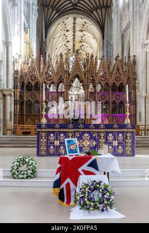 Winchester, Hampshire, Großbritannien. 11.. September 2022. Nach dem Tod von Königin Elizabeth II. Am 8.. September 2022 wurde das Innere der Winchester Cathedral in Purpur beleuchtet, mit Bildern der verstorbenen Königin, Blumen und Gebeten. Viele Menschen sind heute gekommen, um still und leise ihren Respekt zu zollen und ihre Ehrungen zu hinterlassen, indem sie ein Kondolenzbuch unterschrieben oder Kerzen angezündet haben. Das Land befindet sich bis zu seiner Beerdigung in einer Phase nationaler Trauer. Stockfoto