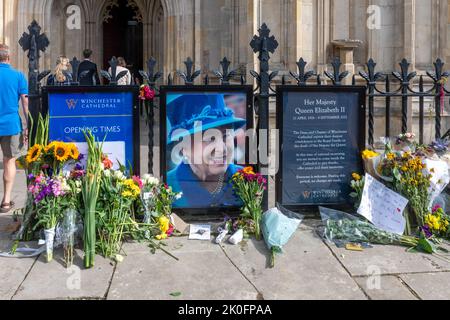 Winchester, Hampshire, Großbritannien. 11.. September 2022. Nach dem Tod von Königin Elizabeth II. Am 8.. September 2022 haben Menschen Blumen und Ehrungen zu Ehren von Königin Elizabeth II. Vor dem Eingang der Winchester Cathedral platziert. Das Land befindet sich bis zu seiner Beerdigung in einer Phase nationaler Trauer. Stockfoto