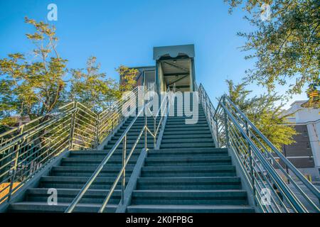 Zwei-Wege-Steg-Treppe mit Geländern dazwischen - Phoenix, Arizona. Treppe mit Betontreppen in der Nähe der Bäume auf der Seite in Richtung eines Fußbr Stockfoto