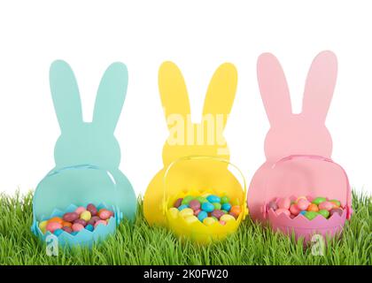 Drei farbenfrohe Osterhasen-Silhouetten aus Holz in blau, gelb und rosa mit dazu passenden farbigen winzigen osterkörben voller Bonbon-Jelly-Bohnen Stockfoto