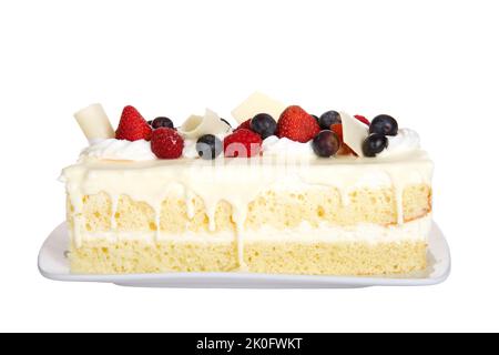 Nahaufnahme einer Vanillekuchen-Tafel mit weißer Schokolade, gekrönt mit frischen Erdbeeren, Himbeeren und Heidelbeeren auf Schlagsahne, garniert mit Cur Stockfoto