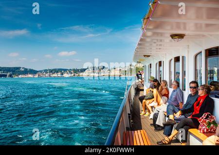 Menschen genießen eine Dampfschifffahrt auf dem Vierwaldstättersee mit der Stadt im Hintergrund, Luzern, Schweiz Stockfoto