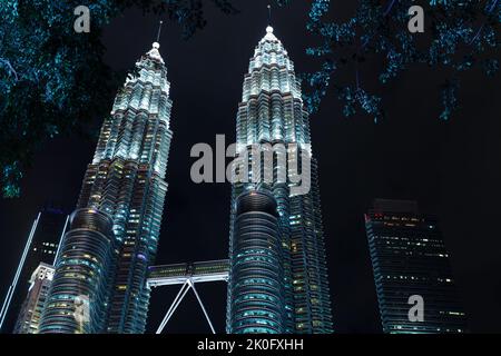 Kuala Lumpur, Malaysia - 28. November 2019: Petronas Twin Towers bei Nacht. Beleuchtete Wolkenkratzer stehen unter dunklem Himmel Stockfoto