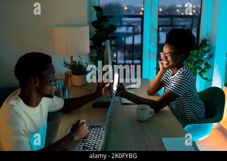 Afroamerikanische Frau zeigt fröhlichen Freund lustige Nachrichten auf dem Smartphone lachend und lächelnd Stockfoto
