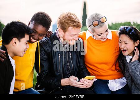 Fröhliche junge Gruppe von studentischen Freunden, die Spaß mit dem Handy haben Stockfoto