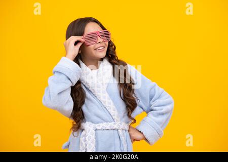 Portrait von Teenager-Mädchen in lustigen Brillen und Pyjama oder Hausbademantel Gefühl Spaß isoliert auf gelbem Hintergrund. Kinder-Pyjama-Party. Stockfoto